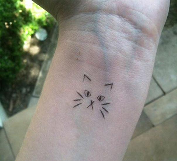 Line art cat tattoo on a wrist, showcasing a simple design for cat lovers.