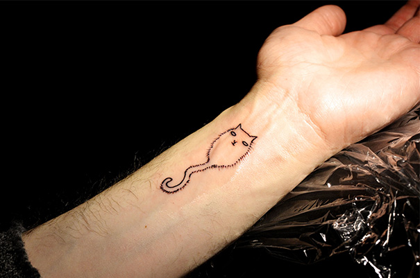 Line art cat tattoo on a forearm, featuring a minimalist design for cat lovers.