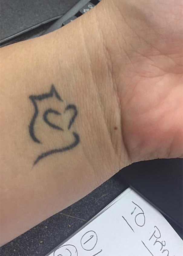 Simple line art cat tattoo on a wrist, showing minimalist design for cat lovers.