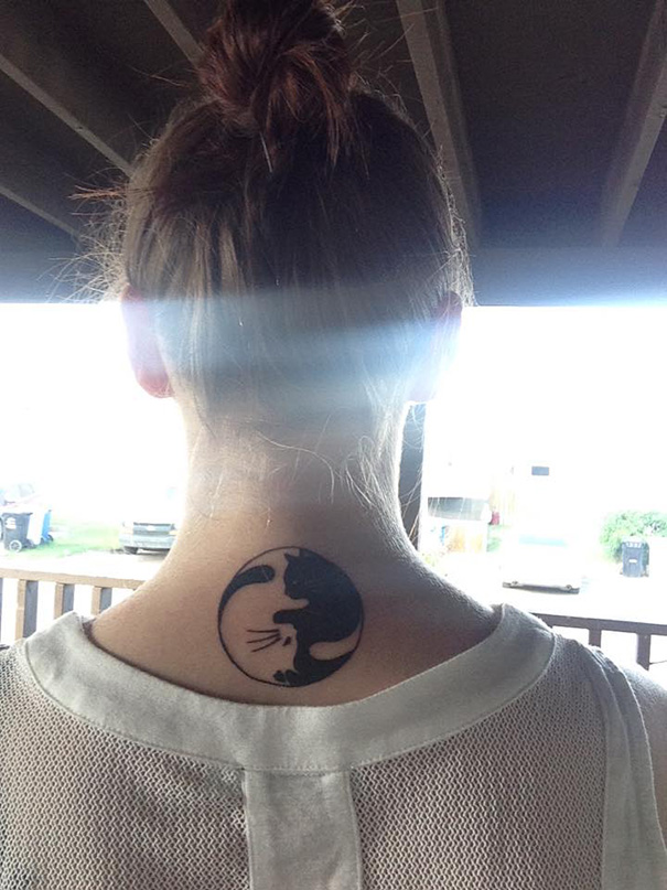 Line art cat tattoo on the back of a woman's neck, featuring a minimalist black and white design.