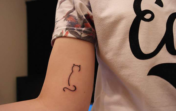 Simple cat tattoo line art on a person's arm, showcasing minimalistic design for cat lovers.