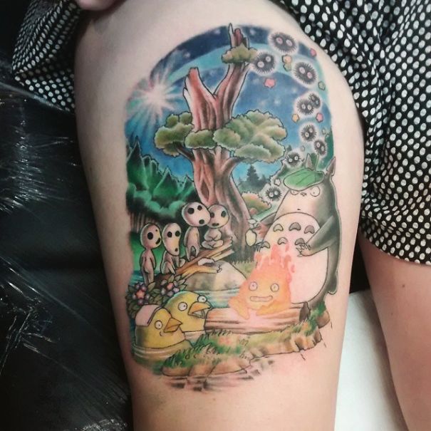 Colorful Studio Ghibli tattoo featuring Totoro and characters from Miyazaki films on a person's thigh.