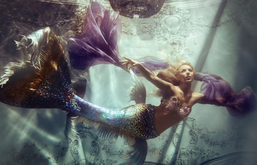 A woman dressed as a mermaid underwater, wearing a shimmering fish tail, gracefully swimming in a serene pose. A woman dressed as a mermaid underwater, wearing a shimmering fish tail, gracefully swimming in a serene pose.