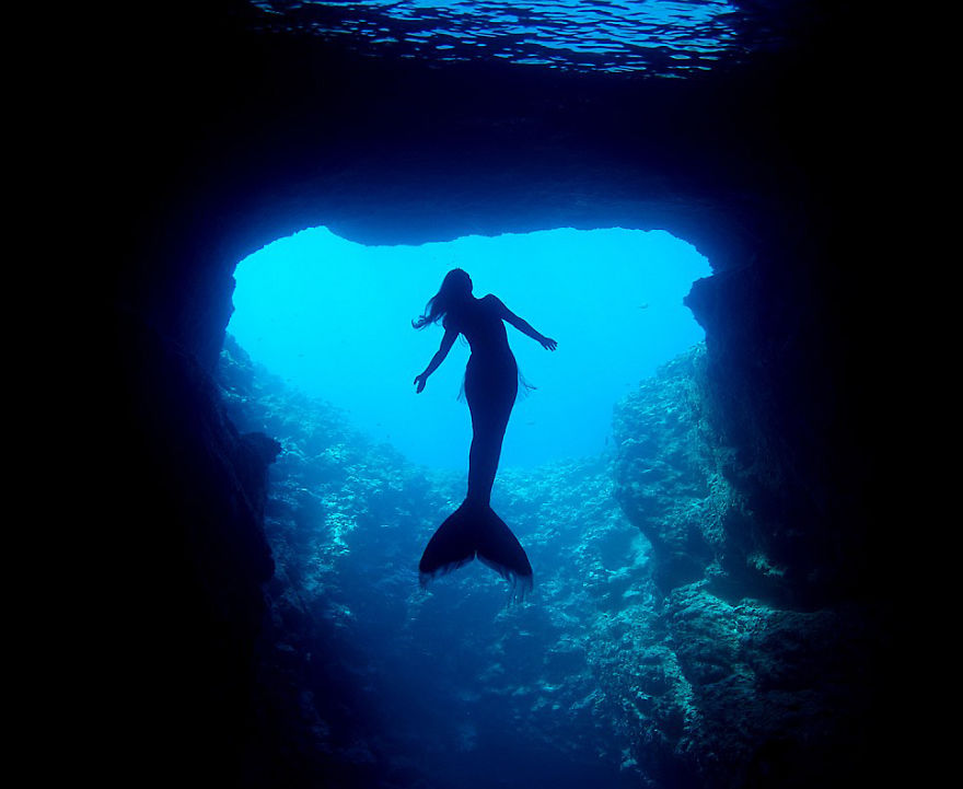 Mermaid with fish tail swimming underwater in a cave, highlighting her ability to hold breath. Mermaid with fish tail swimming underwater in a cave, highlighting her ability to hold breath.