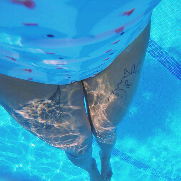 Underwater view of Studio Ghibli tattoos featuring Totoro on a person's thighs, inspired by Miyazaki films.