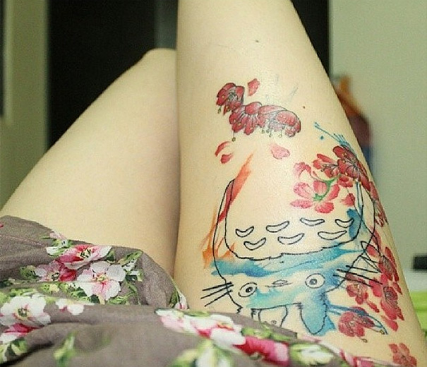 Studio Ghibli tattoo on thigh featuring Totoro with cherry blossoms in watercolor style.