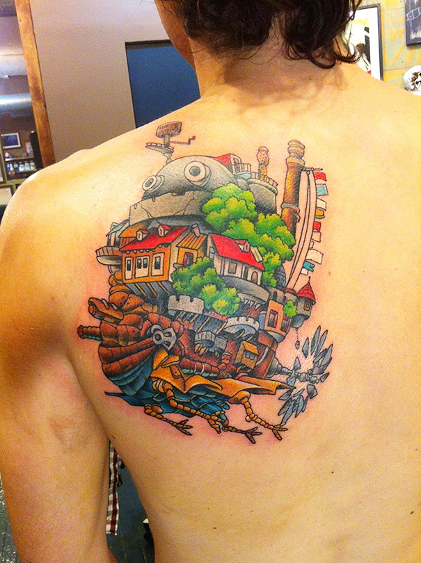 Studio Ghibli tattoo on back, inspired by Miyazaki films, featuring colorful scenery and characters in detailed design.