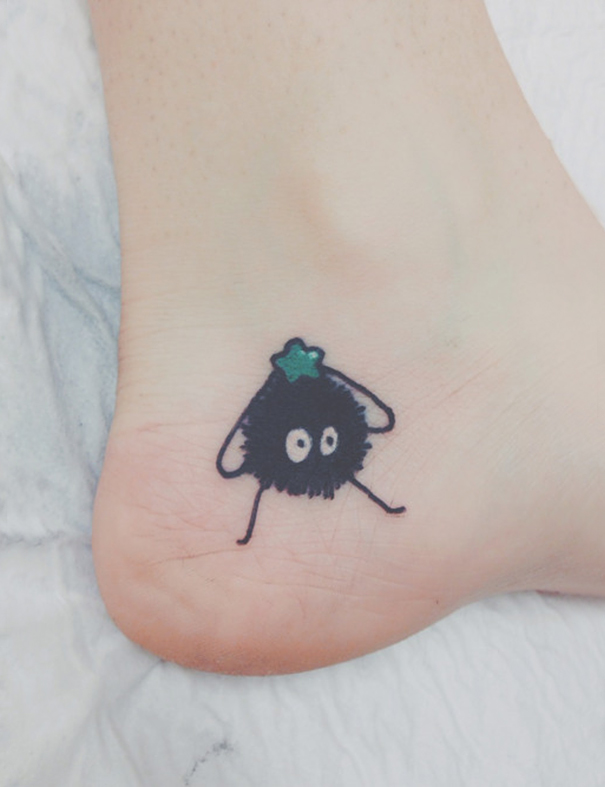 Studio Ghibli-inspired tattoo on a foot featuring a soot sprite with a green star.