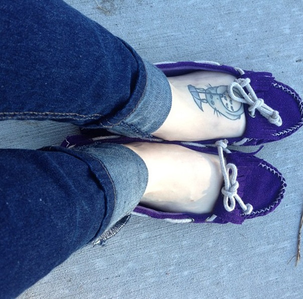 Purple shoes and jeans showing Studio Ghibli tattoo on foot featuring a character inspired by Miyazaki films.