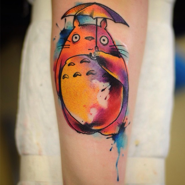 Colorful Studio Ghibli tattoo inspired by Miyazaki films, featuring Totoro holding an umbrella.