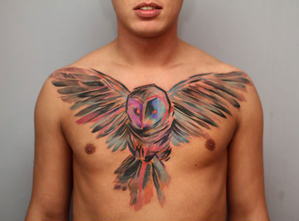 Man with a colorful watercolor owl tattoo on his chest, showcasing detailed art by Czech artist. Man with a colorful watercolor owl tattoo on his chest, showcasing detailed art by Czech artist.