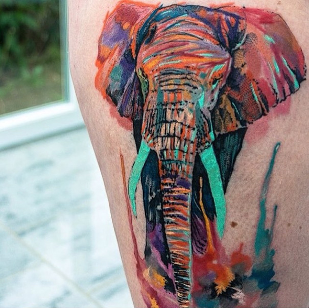 Vibrant watercolor tattoo of an elephant by Czech artist Ondrash displayed on skin.