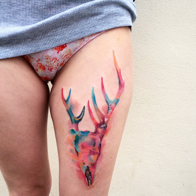 Colorful watercolor tattoo of a deer skull on a thigh, showcasing Czech artist Ondrash's artistry. Colorful watercolor tattoo of a deer skull on a thigh, showcasing Czech artist Ondrash's artistry.
