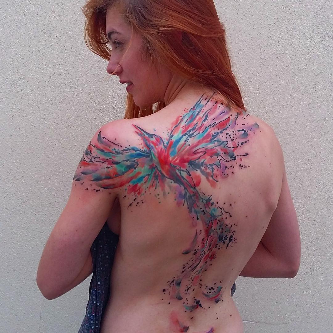 Woman showcasing a vibrant watercolor tattoo on her back, featuring abstract colors and patterns. Woman showcasing a vibrant watercolor tattoo on her back, featuring abstract colors and patterns.