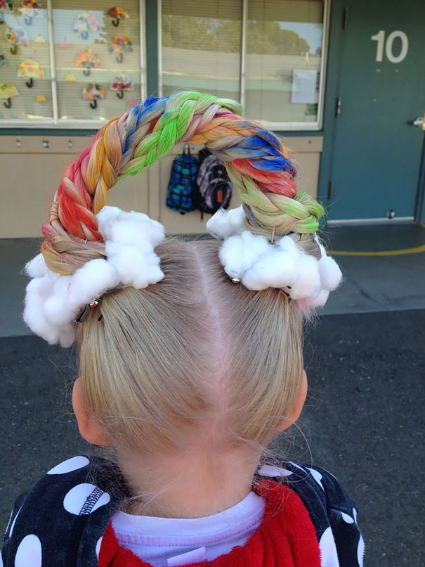 Child with colorful braided hair shaped like a rainbow, adorned with cotton clouds for Crazy Hair Day.