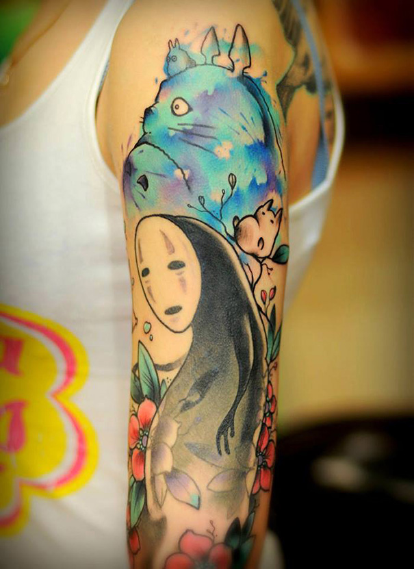 Tattoo featuring Studio Ghibli characters, inspired by Miyazaki films, on a person's arm with colorful floral accents.