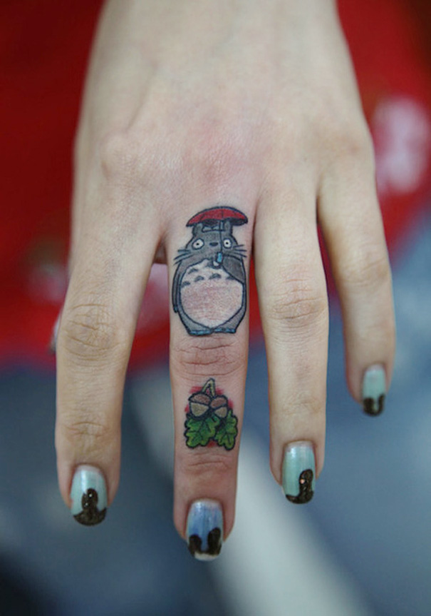 Studio Ghibli tattoo on a finger, featuring a Totoro character and leaf detail, inspired by Miyazaki films.