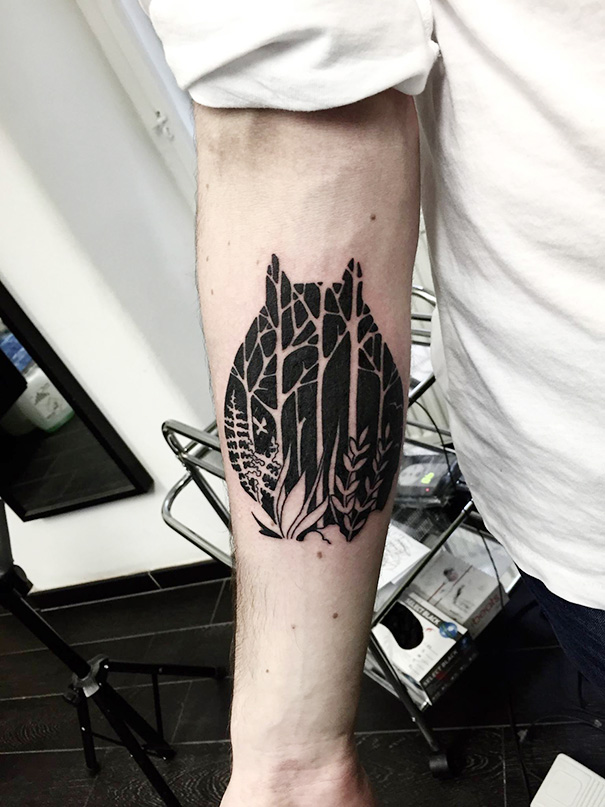 Studio Ghibli tattoo of Totoro silhouette with forest design on forearm.