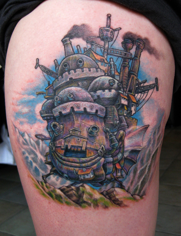 Studio Ghibli tattoo of a colorful, detailed castle from Howl's Moving Castle inspired by Miyazaki films, inked on a person's thigh.