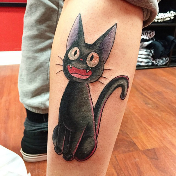 Studio Ghibli tattoo of Jiji the cat, inspired by Miyazaki films, on the lower leg, featuring bright colors and bold outlines.