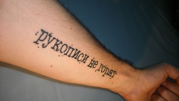 Tattoo of a book quote in Cyrillic script on a person's forearm.