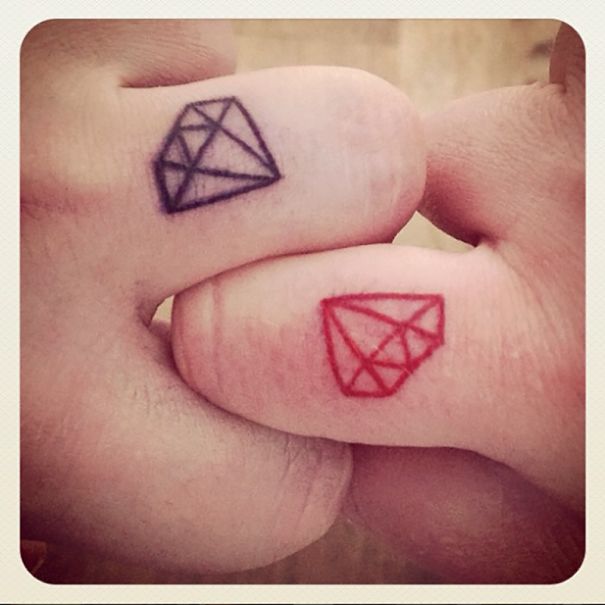 Matching wedding tattoos on fingers with diamond designs in black and red.