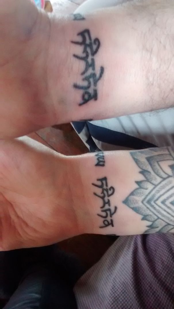 Matching wedding tattoos on wrists with Sanskrit script text.