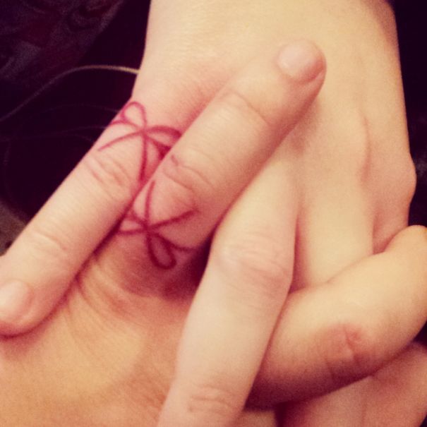 Matching wedding tattoos of bows on couple's ring fingers symbolize their brave commitment to each other.