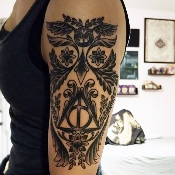 Ornate tattoo inspired by a book featuring symbolic floral and geometric designs on an arm.
