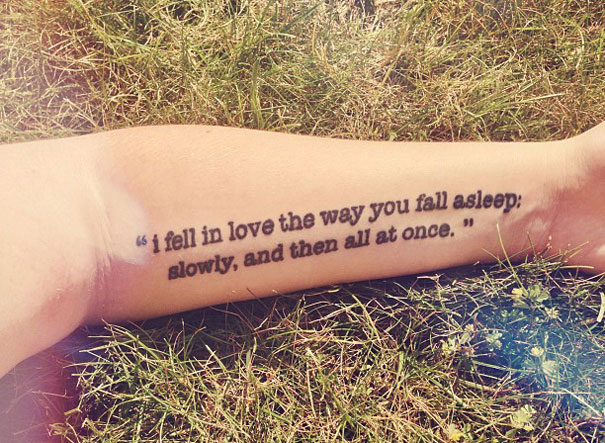 Tattoo of a book quote on an arm, lying on grass, perfect for bookworms.