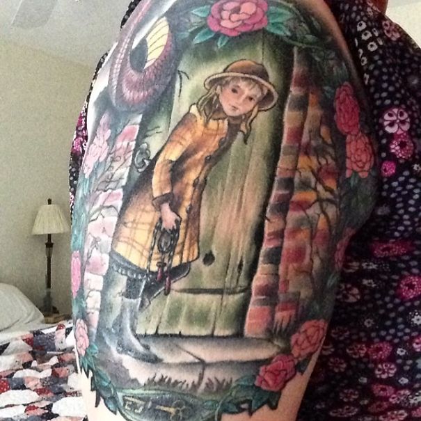 Colorful book-inspired tattoo featuring a girl in a yellow coat surrounded by flowers and a mystical setting.