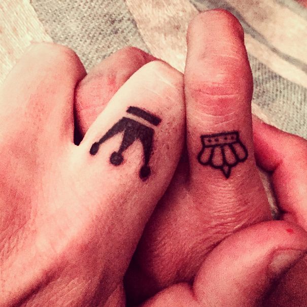 Matching wedding tattoos with crown designs on couple's fingers.