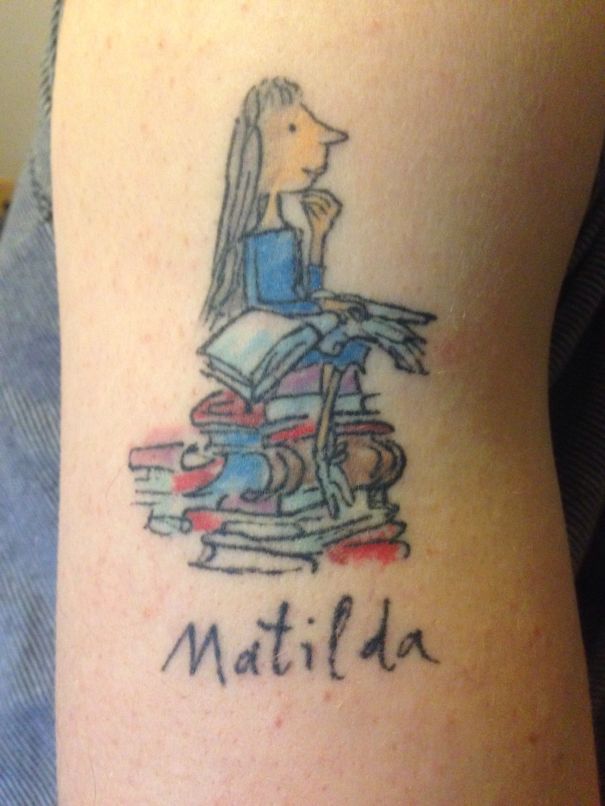 Tattoo of Matilda from Roald Dahl's book, sitting on a stack of colorful books.