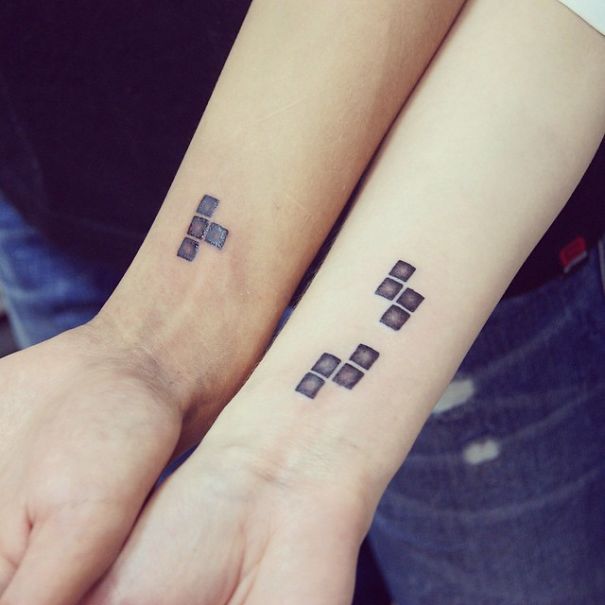 Matching wedding tattoos on couple's forearms, featuring black square patterns.