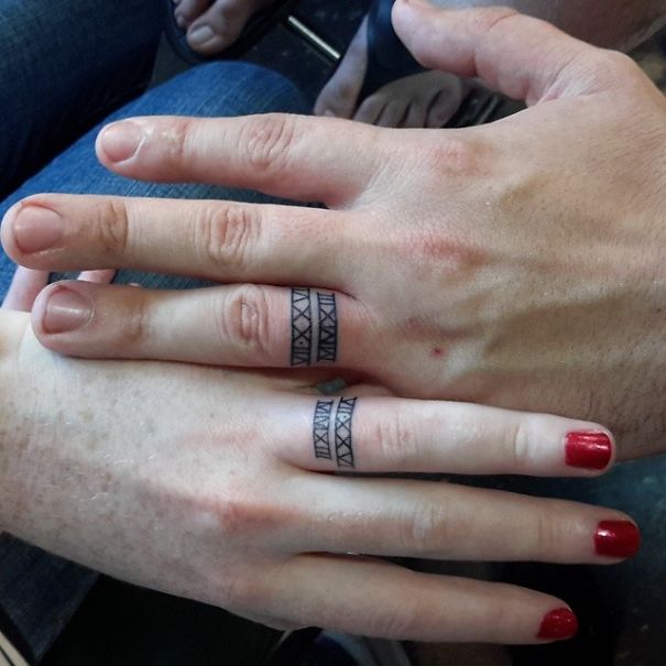 Couple's matching wedding tattoos instead of rings on their fingers.