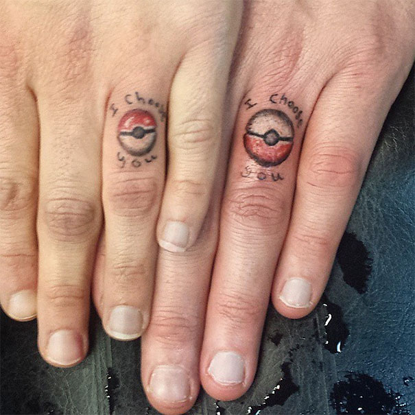 Matching wedding tattoos on fingers with Pokéball design and "I choose you" text.