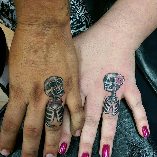Matching wedding tattoos featuring skeletons on a couple's hands, symbolizing their brave commitment.