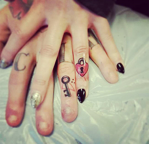 Matching wedding tattoos of a key and heart lock on couple's fingers.