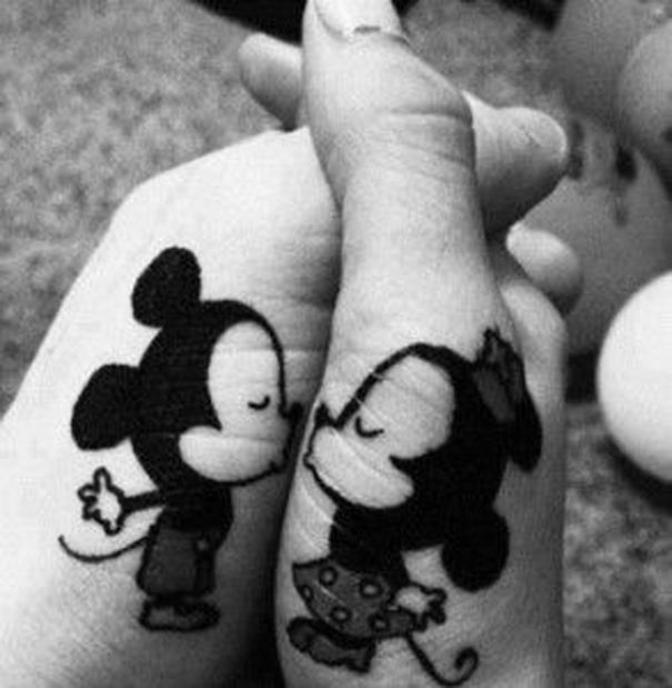 Matching wedding tattoos of a Mickey Mouse-inspired couple on intertwined hands.
