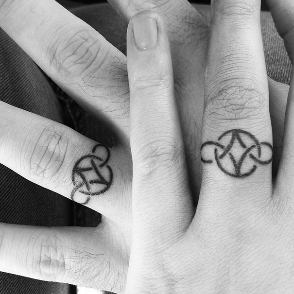 Matching wedding tattoos of intertwined Celtic designs on couple's ring fingers.