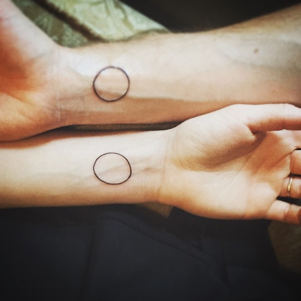Matching wedding tattoos of circles on wrists, symbolizing commitment and love.
