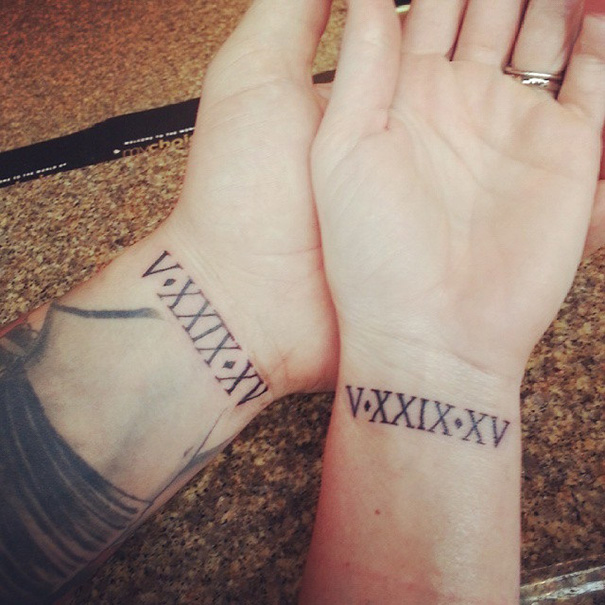 Matching roman numeral wedding tattoos on couple's wrists.