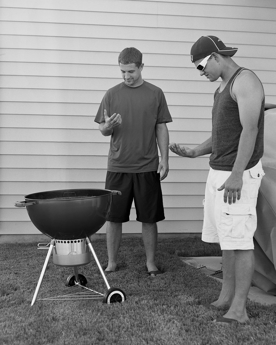 Two men standing by a grill holding invisible phones in their hands, illustrating phone addiction removal concept. Two men standing by a grill holding invisible phones in their hands, illustrating phone addiction removal concept.