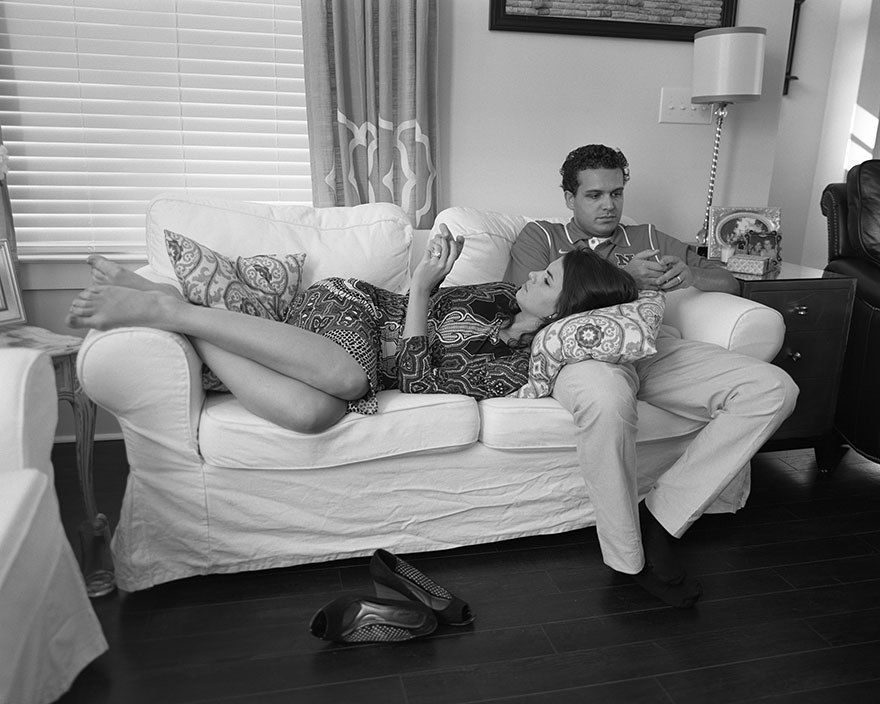 Man and woman in a living room sitting on a couch, phones removed to highlight our terrible phone addiction in modern portraits. Man and woman in a living room sitting on a couch, phones removed to highlight our terrible phone addiction in modern portraits.