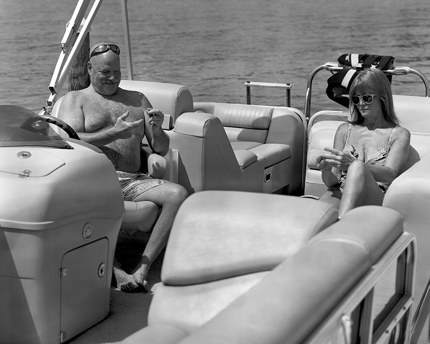 Black and white photo of two people on a boat, with devices digitally removed to show phone addiction impact. Black and white photo of two people on a boat, with devices digitally removed to show phone addiction impact.