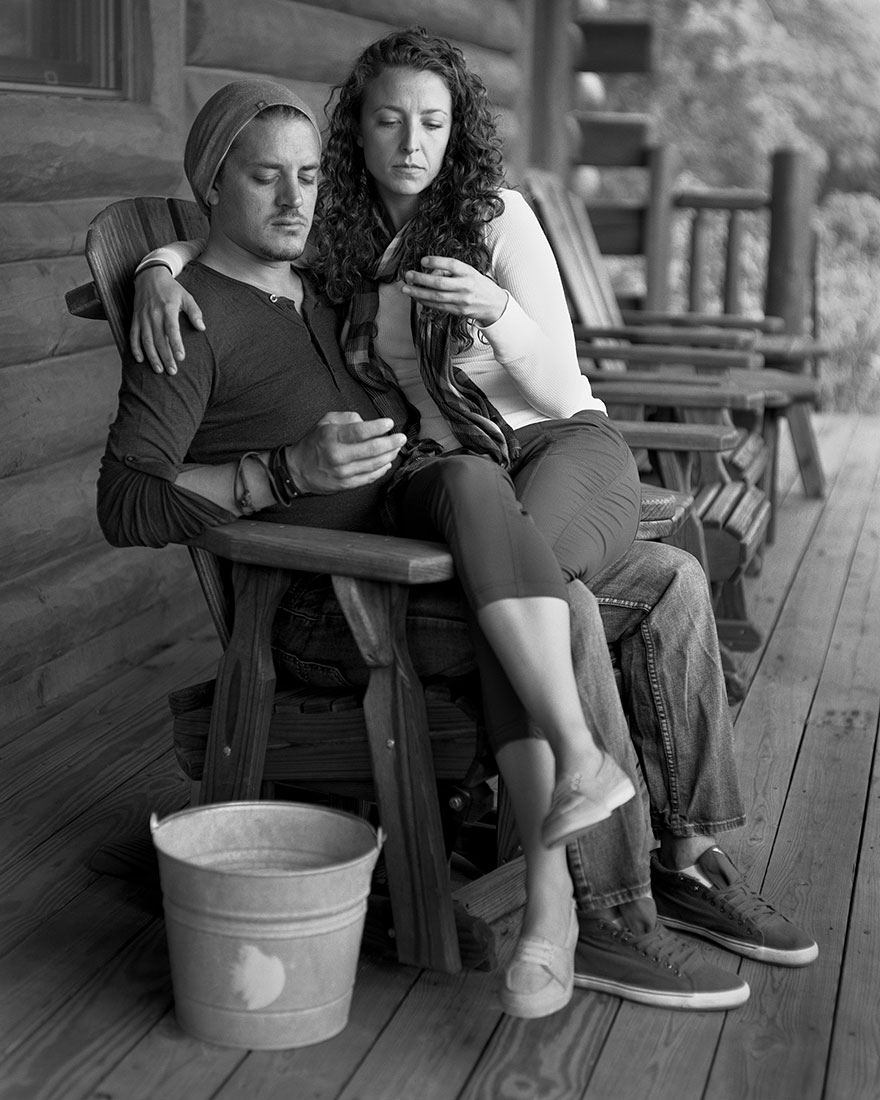 Couple sitting on wooden porch chairs, edited to remove phones, highlighting smartphone addiction in black and white. Couple sitting on wooden porch chairs, edited to remove phones, highlighting smartphone addiction in black and white.