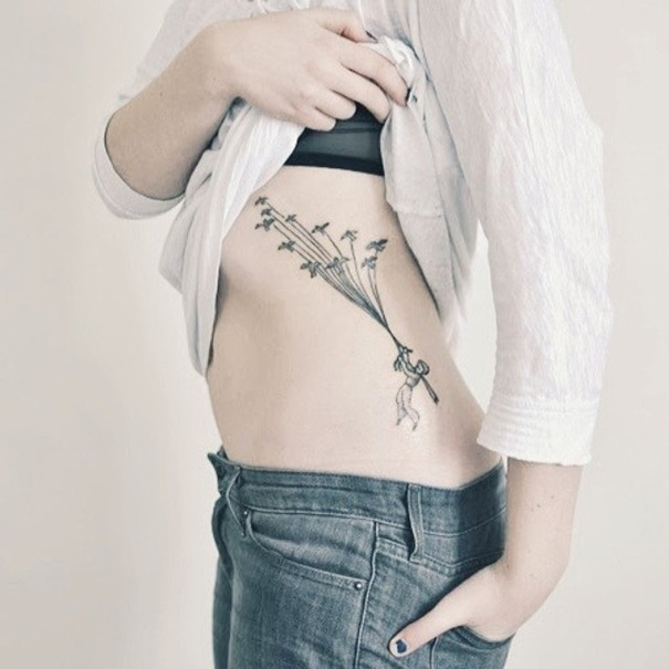 Book-inspired tattoo featuring a whimsical design on a person's side.