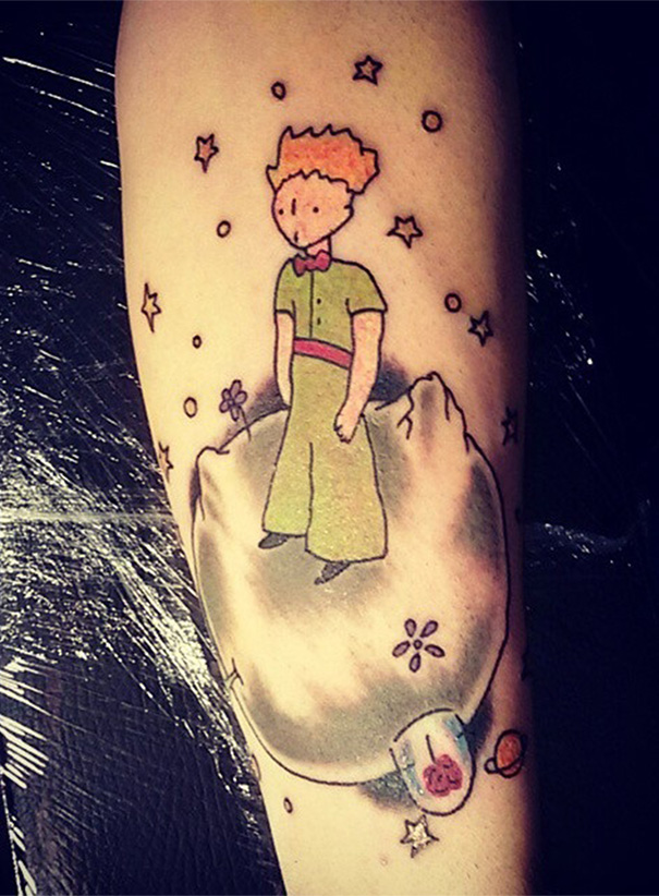 Tattoo of a book character standing on a planet, surrounded by stars, perfect for bookworms seeking inspiration.