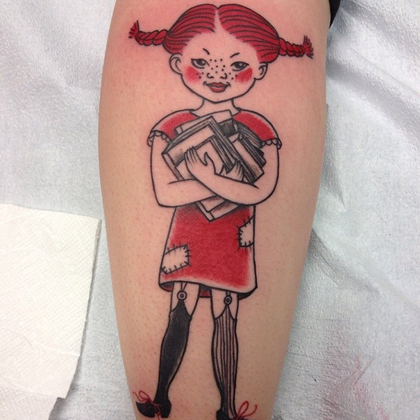 Tattoo of a girl holding books, inspired by literature, with red hair and patchwork dress on leg.