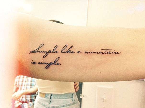 Tattoo of a book-inspired quote in cursive script on a person's forearm.